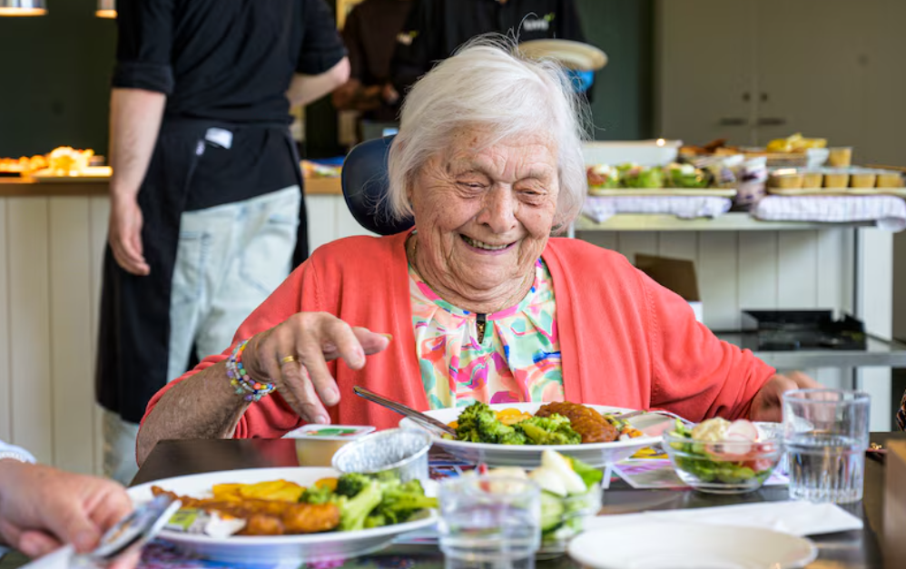 Mevrouw eet een heerlijke maaltijd op locatie De Broekheurnerstede