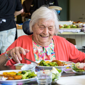 Mevrouw eet een heerlijke maaltijd op locatie De Broekheurnerstede